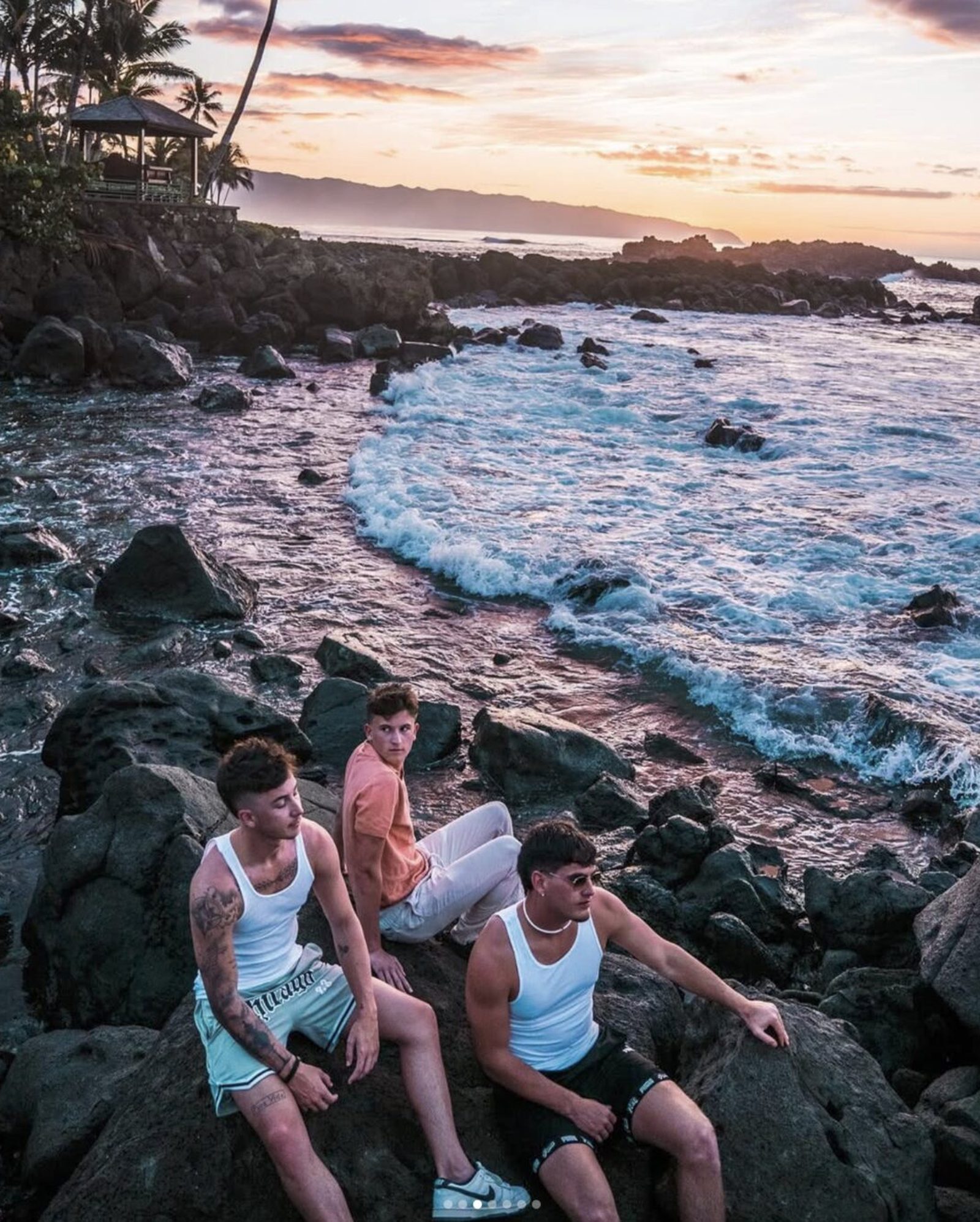 Valor reps sitting on volcanic rocks watching the sunset in Hawaii