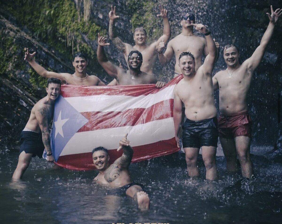 Valor reps holding the Puerto Rican flag under a waterfall on a team trip to Puerto Rico